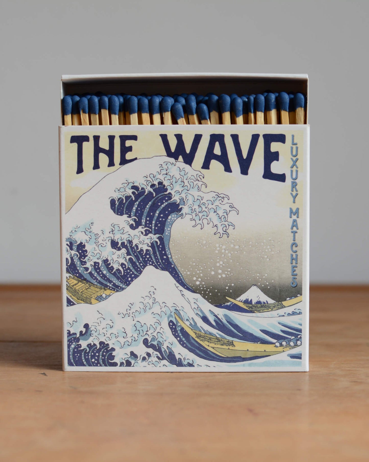 A matchbox featuring a Japanese illustration of a wave.