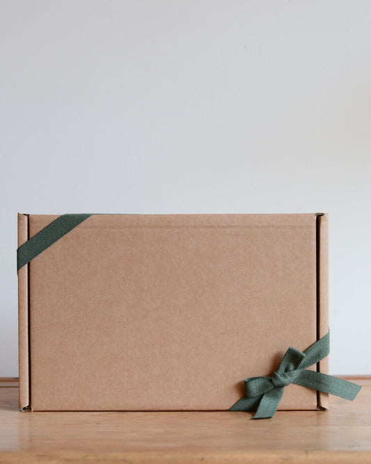 A kraft gift box, tied with a green cotton ribbon.