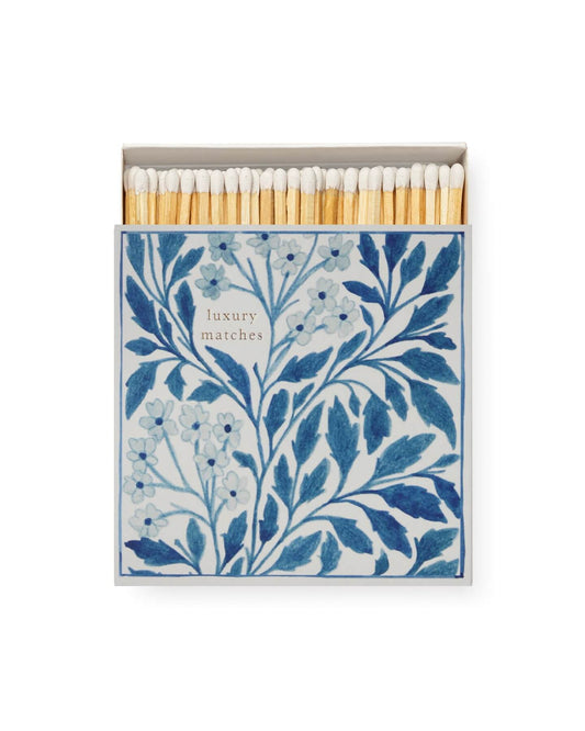 A blue and white match box with a botanical print design.