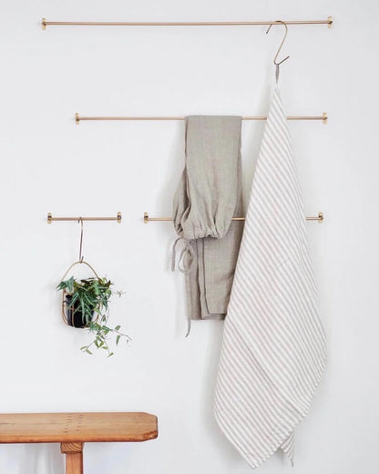 A collection of solid brass hanging rails, displaying towels, clothing and plants.