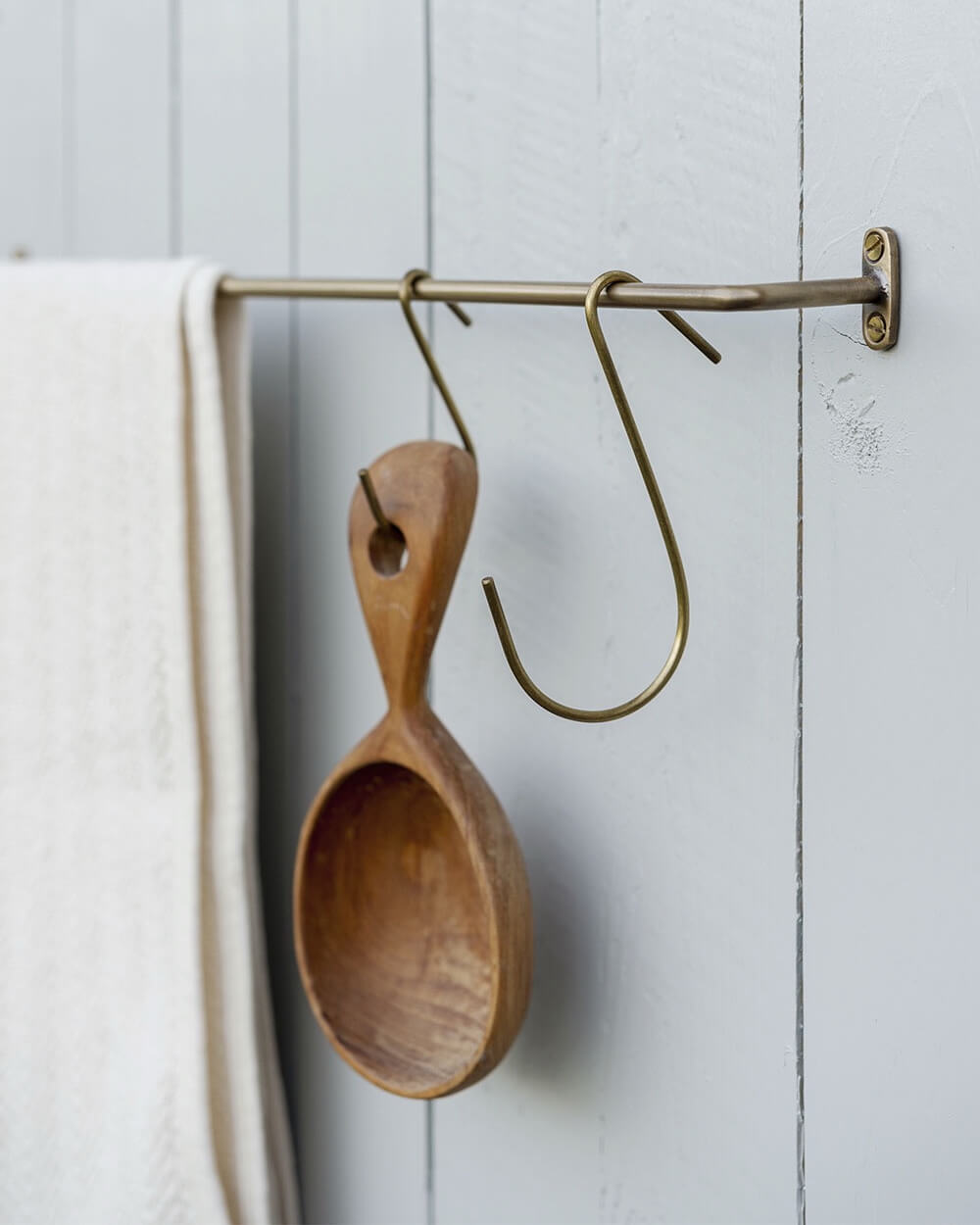 A small solid brass hanging rail, with brass S hooks and utensils.