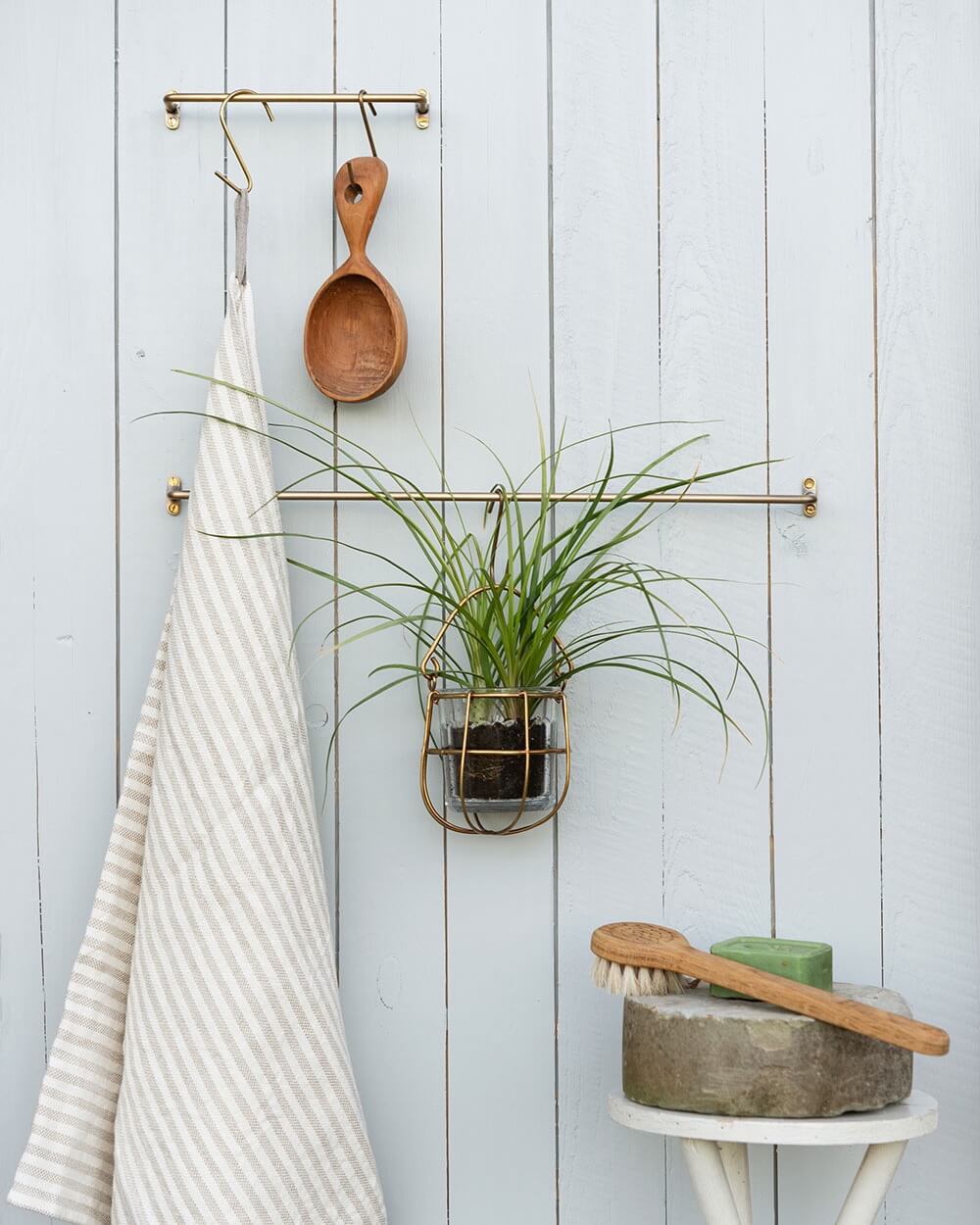 A pair of solid brass hanging rails, holding bath accessories and towels.