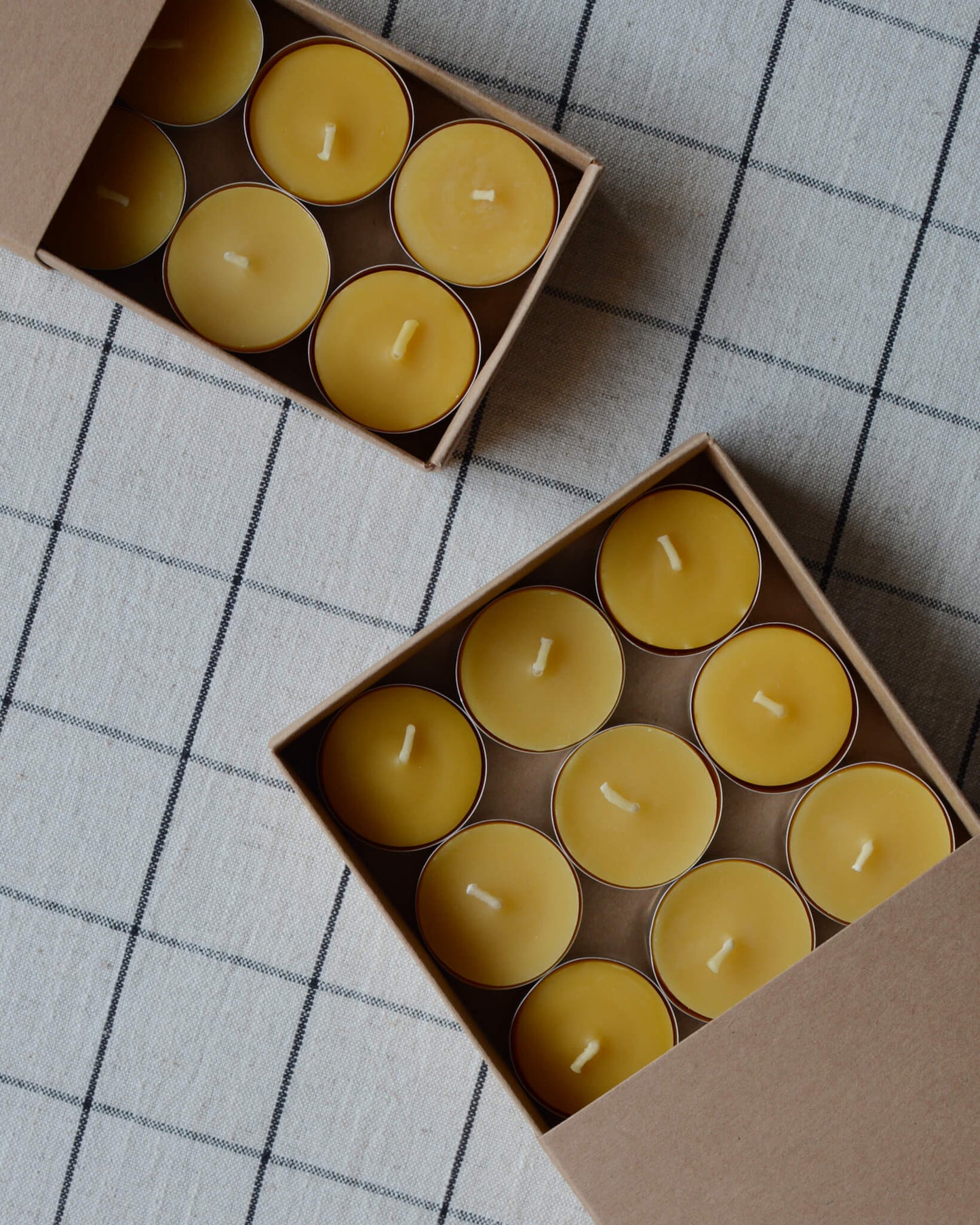 Golden yellow beeswax tealights in kraft boxes.