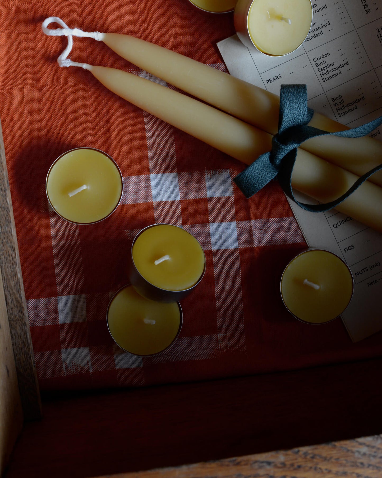 Yellow beeswax tealights and dinner candles, shown in a drawer.