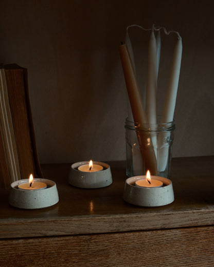 Lit beeswax tealights in ceramic holders.