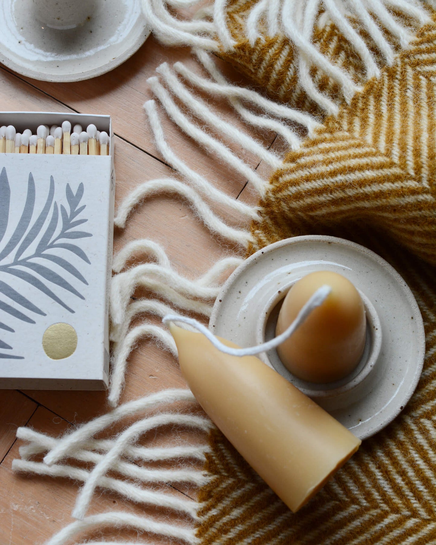 An oatmeal ceramic candle holder and beeswax candles.