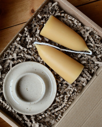 A gift box with an oatmeal ceramic candle holder and beeswax candles.