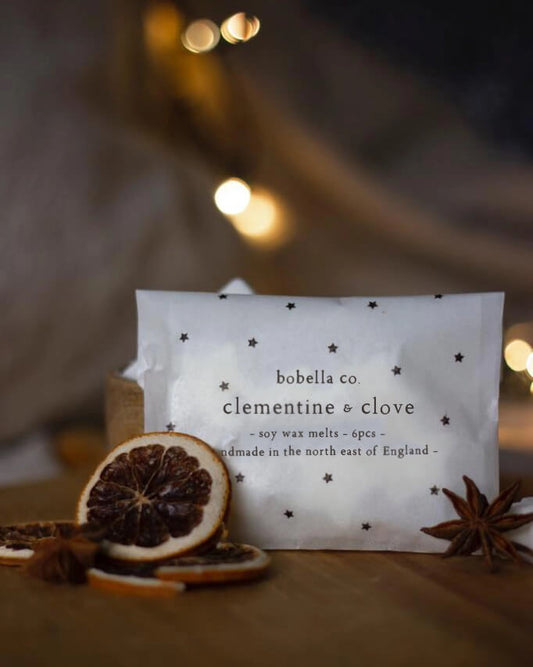 Clementine & clove scented star-shaped wax melts, with orange slices and cloves.