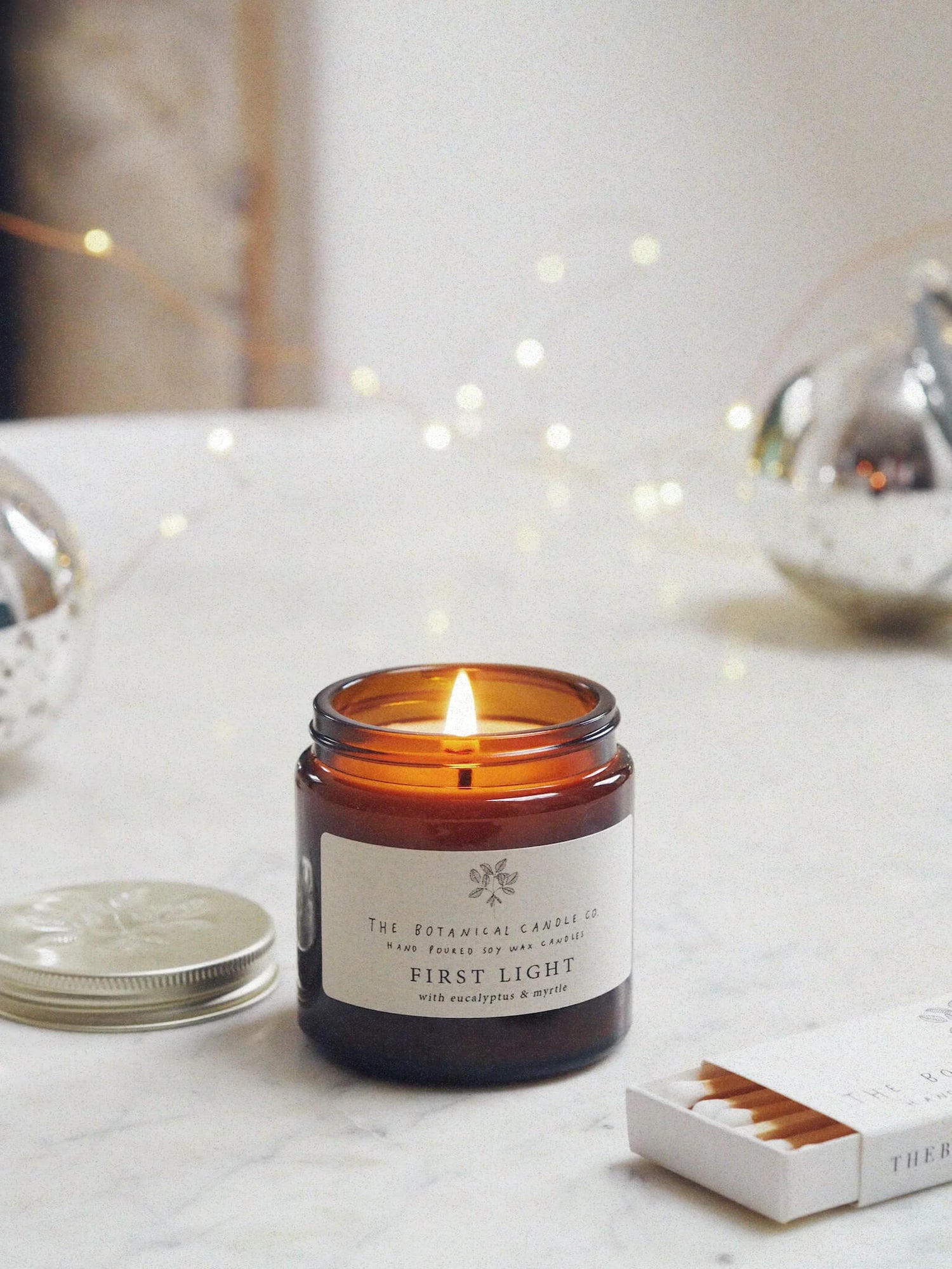 A 120ml eucalyptus and myrtle scented candle in an amber glass jar, surrounded by twinkly lights.