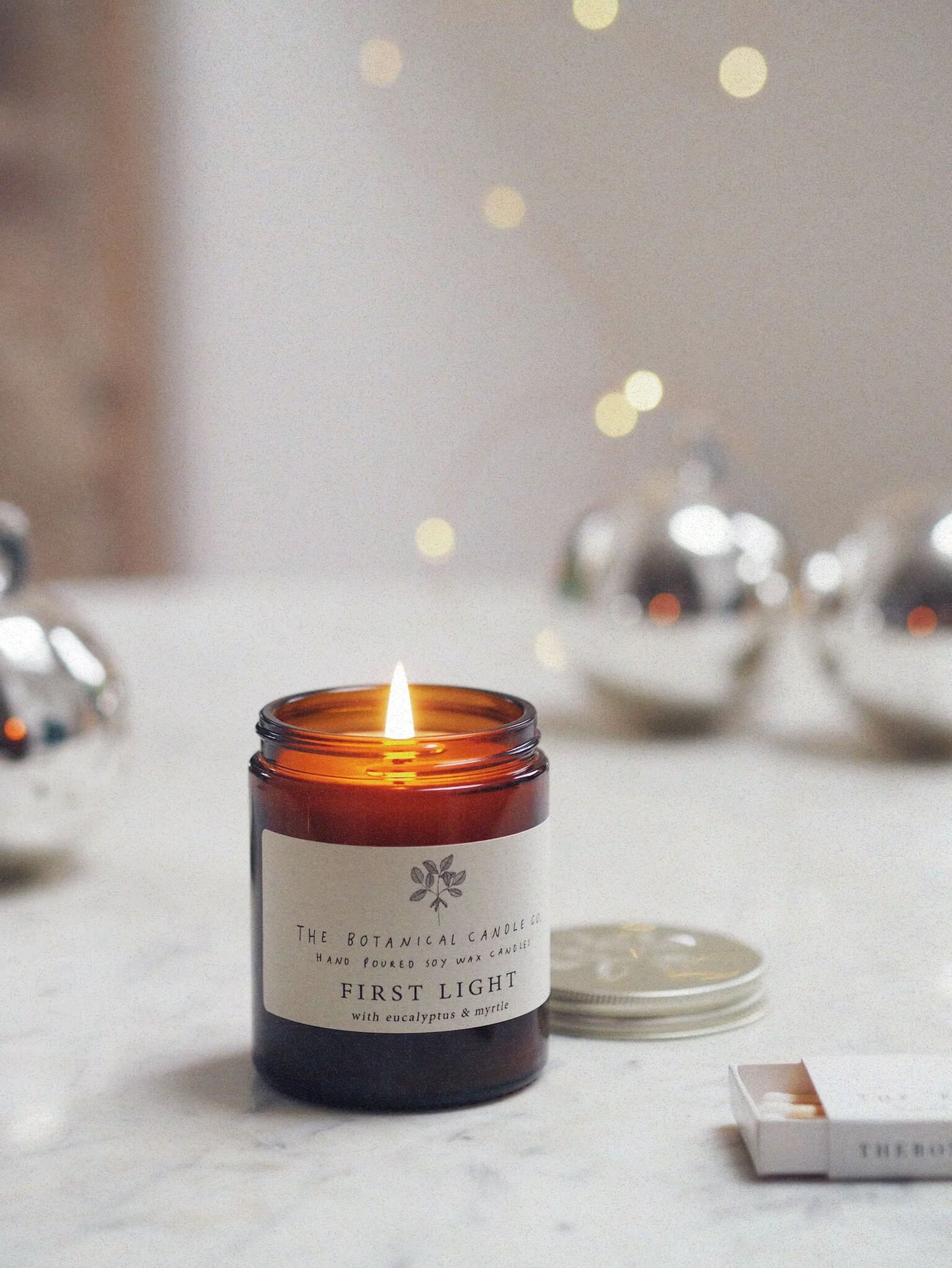 A 180ml eucalyptus and myrtle scented candle in an amber glass jar, surrounded by twinkly lights.