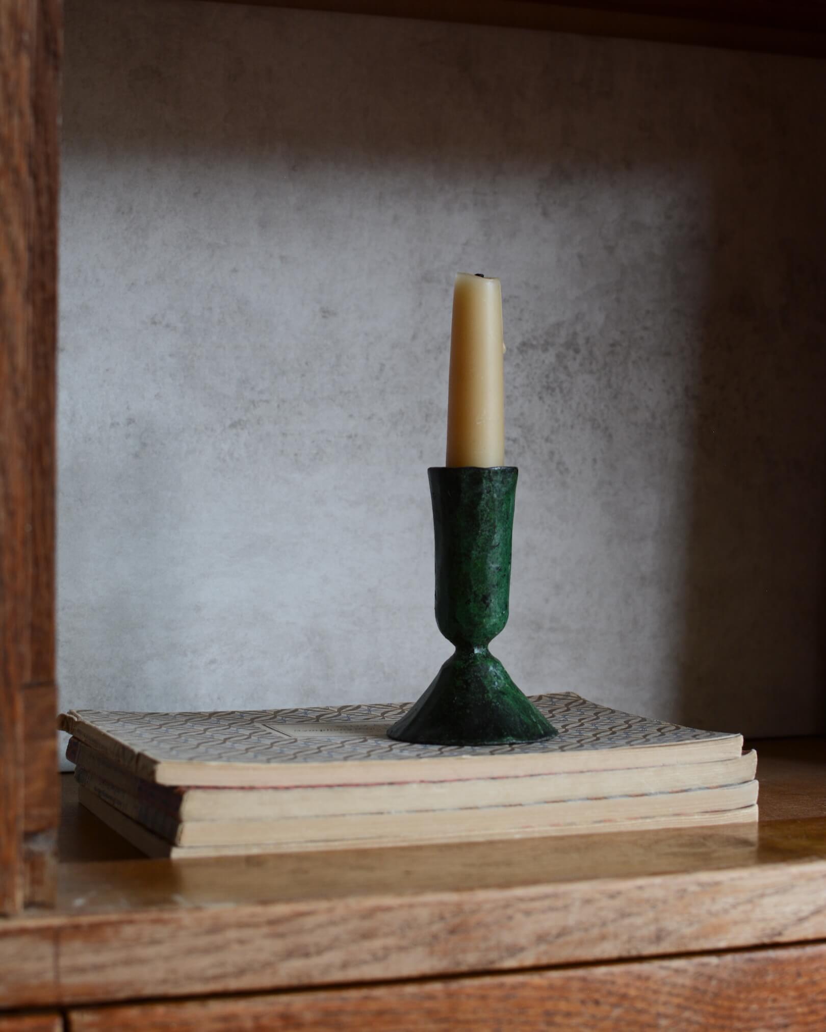 A metal taper candle holder, with a green verdigris finish.