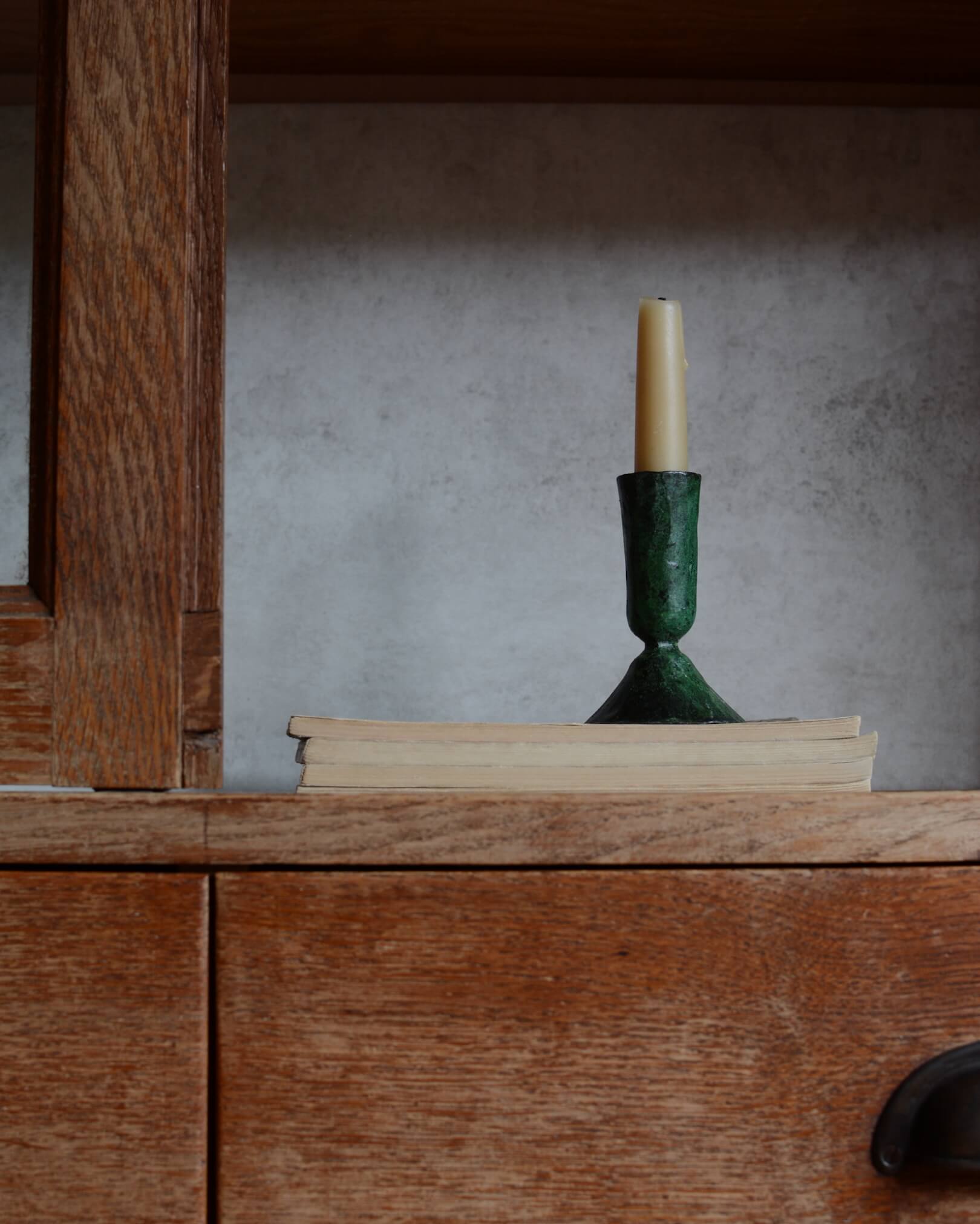 A metal taper candle holder, with a green verdigris finish.