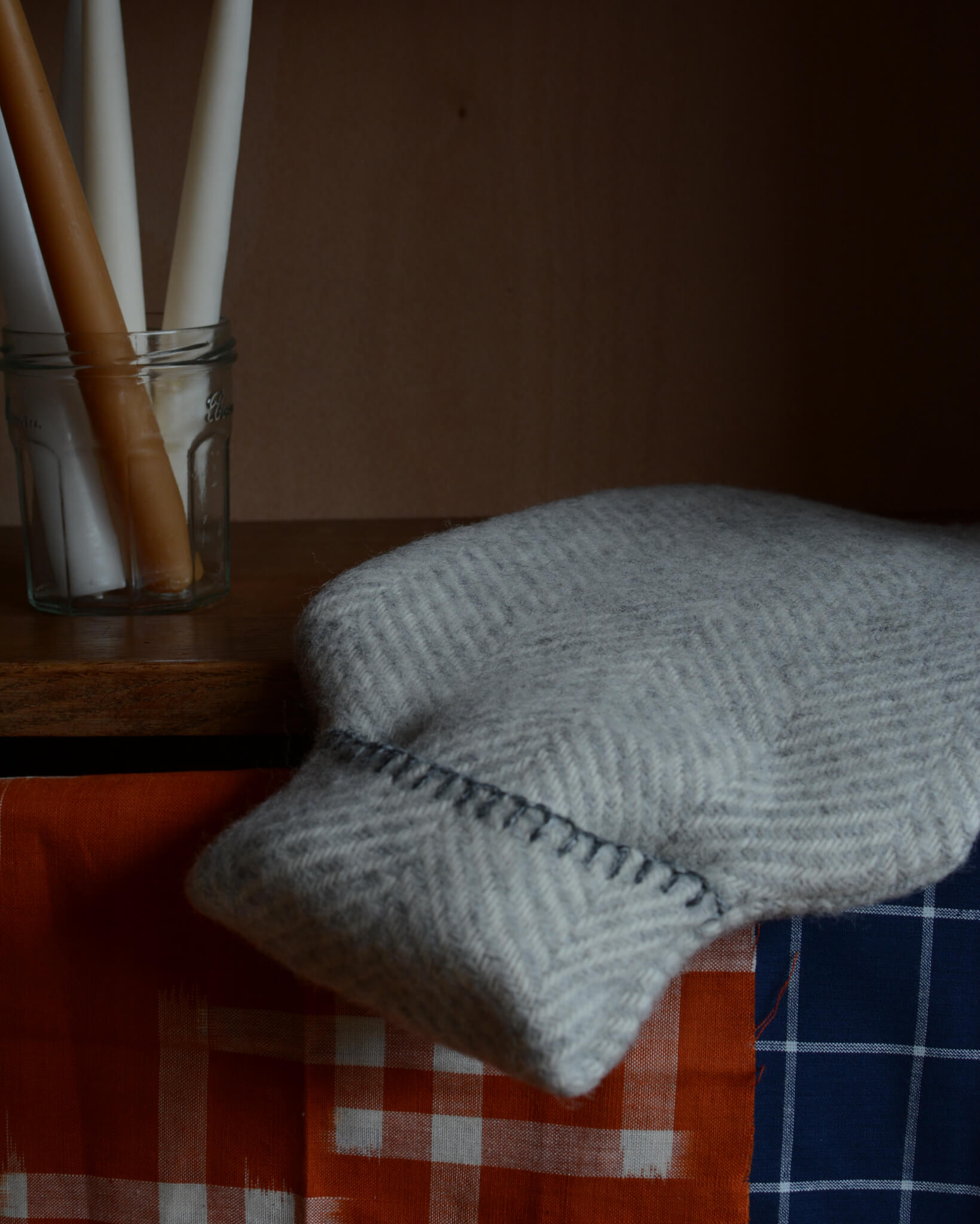 A grey wool hot water bottle, with blanket edge stitching.