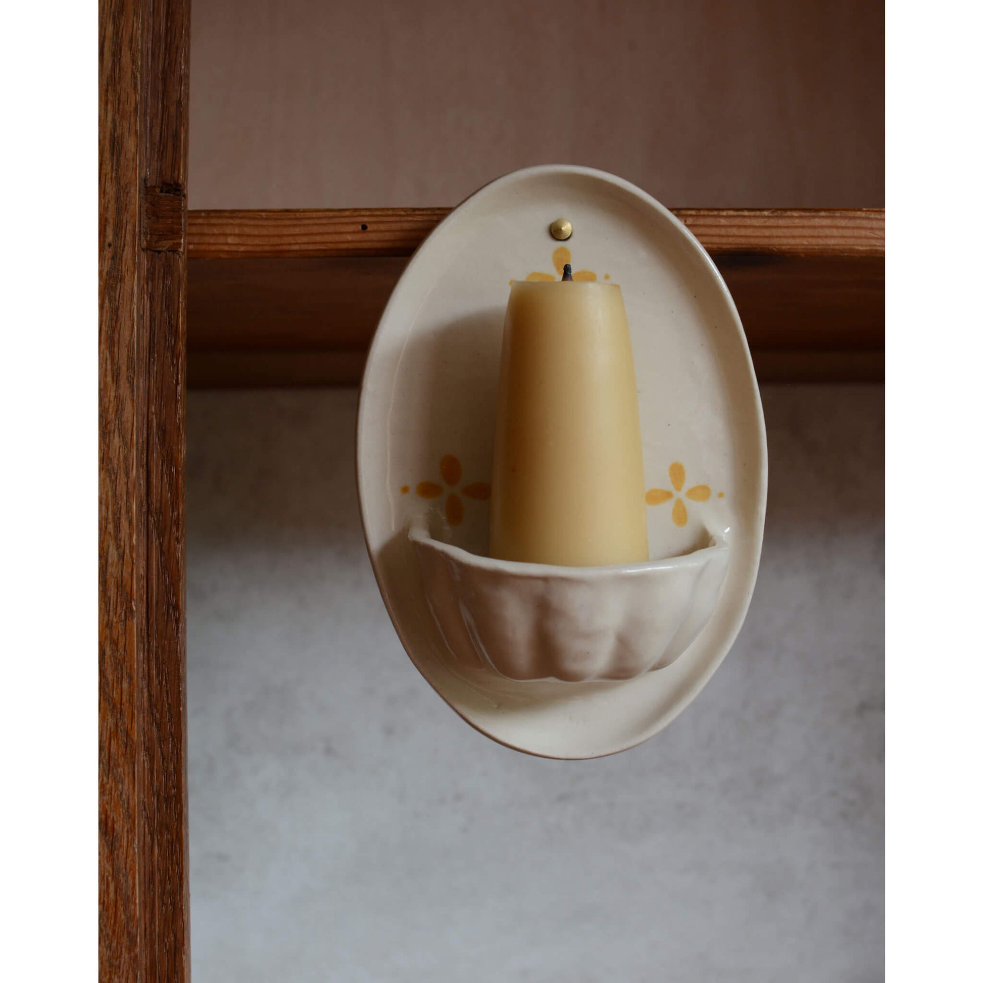 A  close up of a cream and yellow ceramic candle wall sconce.