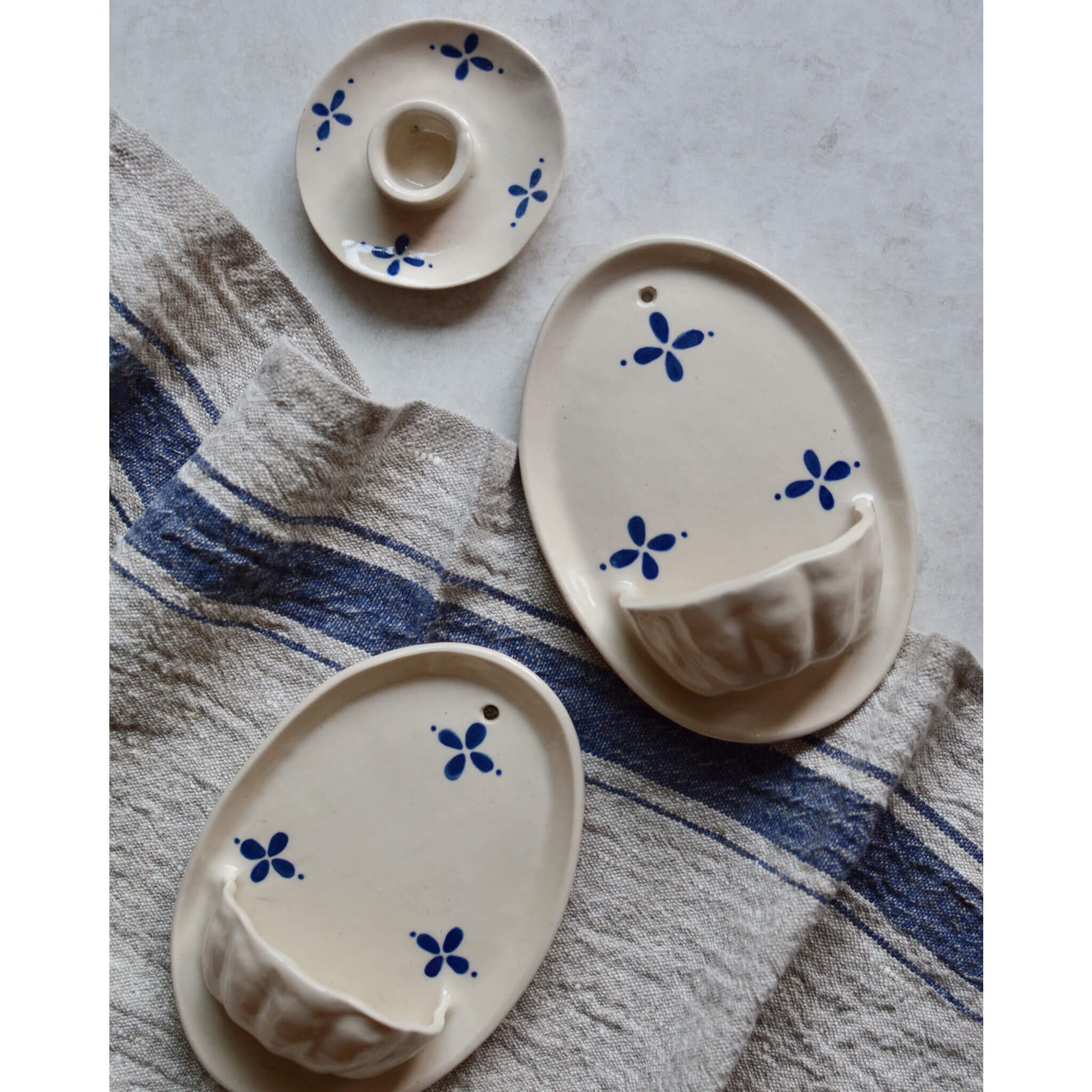 Flatlay image of a collection of cream and blue ceramic candle holders and wall sconces.