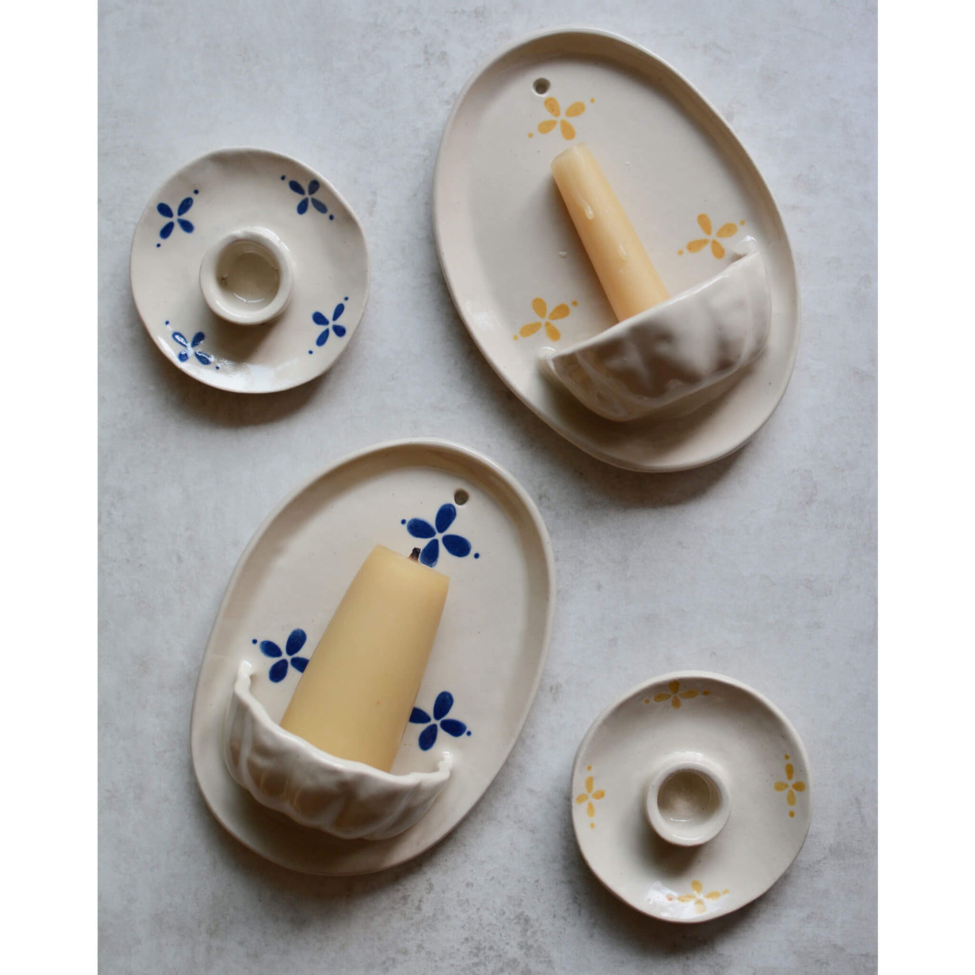 A flatlay image of cream ceramic pieces with yellow or blue stylized floral pattern.