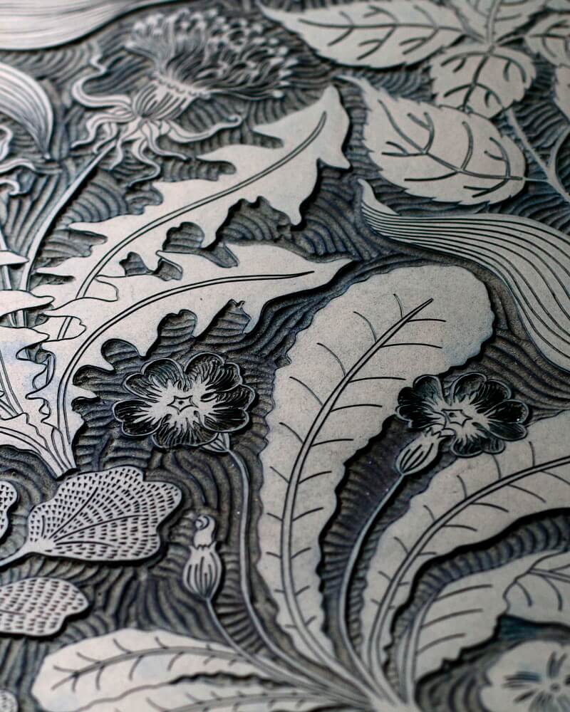 Detail shot of a linocut block depicting Spring flowers and plants.