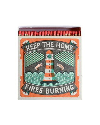 A letterpress design match box with an illustration of a lighthouse and the words 'keep the home fires burning'.