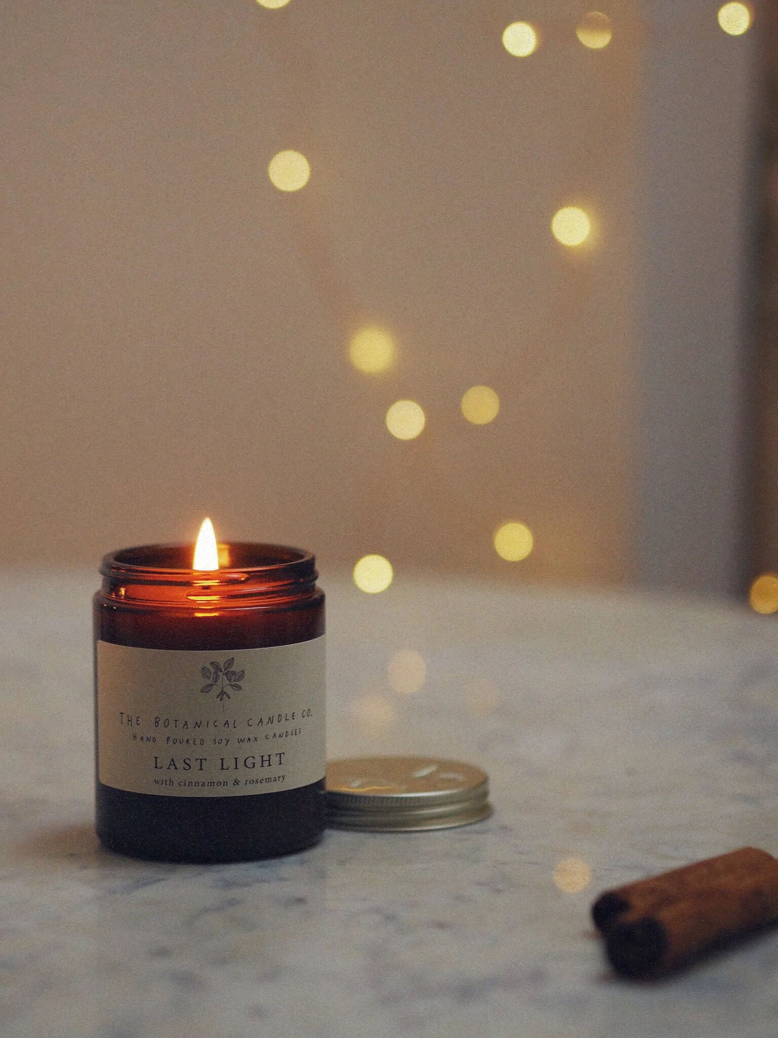 A 180ml Christmas blend scented candle in an amber glass jar, surrounded by twinkly lights.