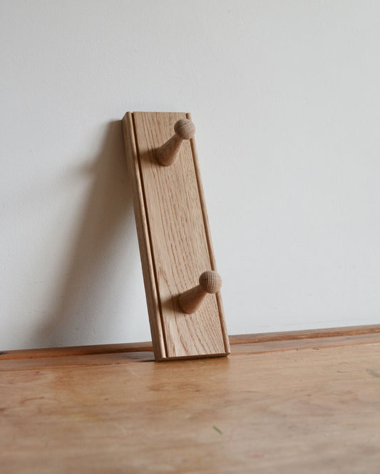 An oak shaker peg rail with 2 pegs.