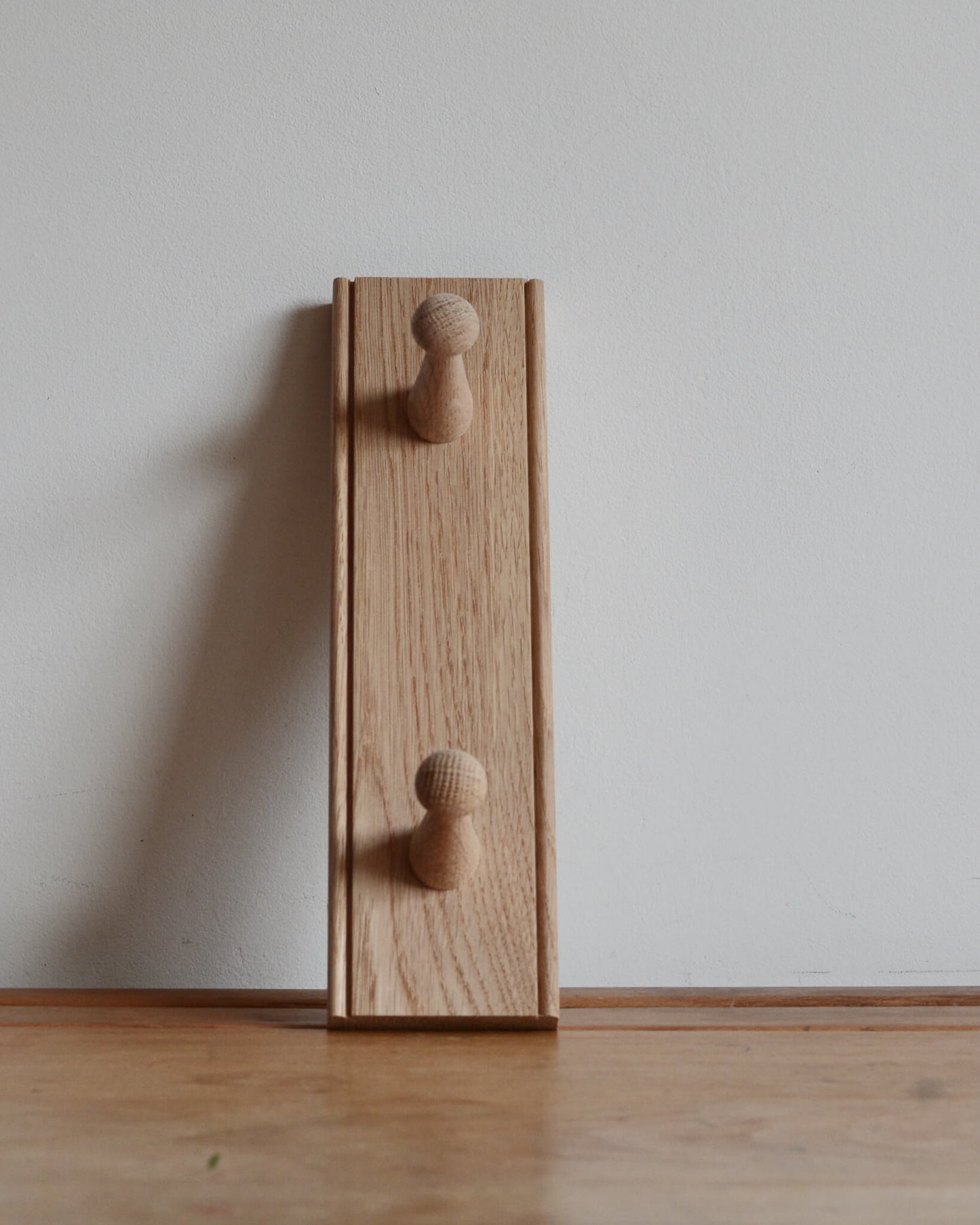 An oak shaker peg rail with 2 pegs.