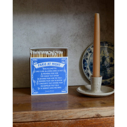 Blue and white matchbox, next to a beeswax candle in candle holder.