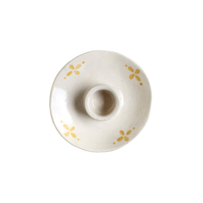 A cream and ochre yellow ceramic candle holder, on a white background.