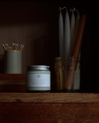 Quiescent scented candle by The Botanical Candle Co, next to beeswax candles and a match pot.