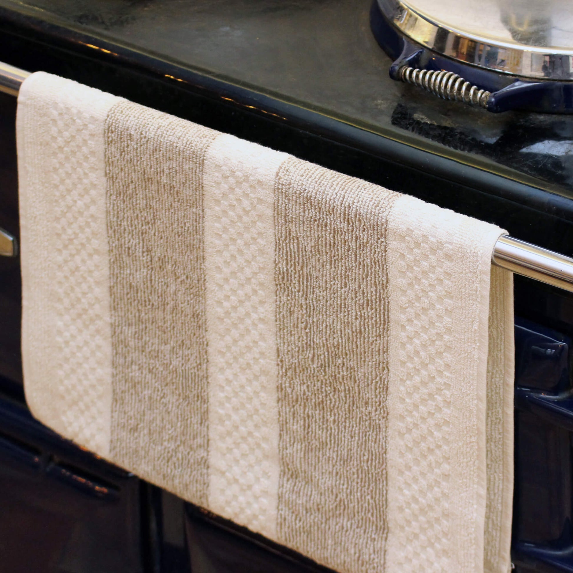 A striped kitchen towel for looping over a range oven handle.