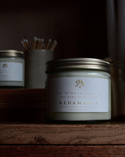 Redamancy scented candle by The Botanical Candle Co, next to a pot of matches.