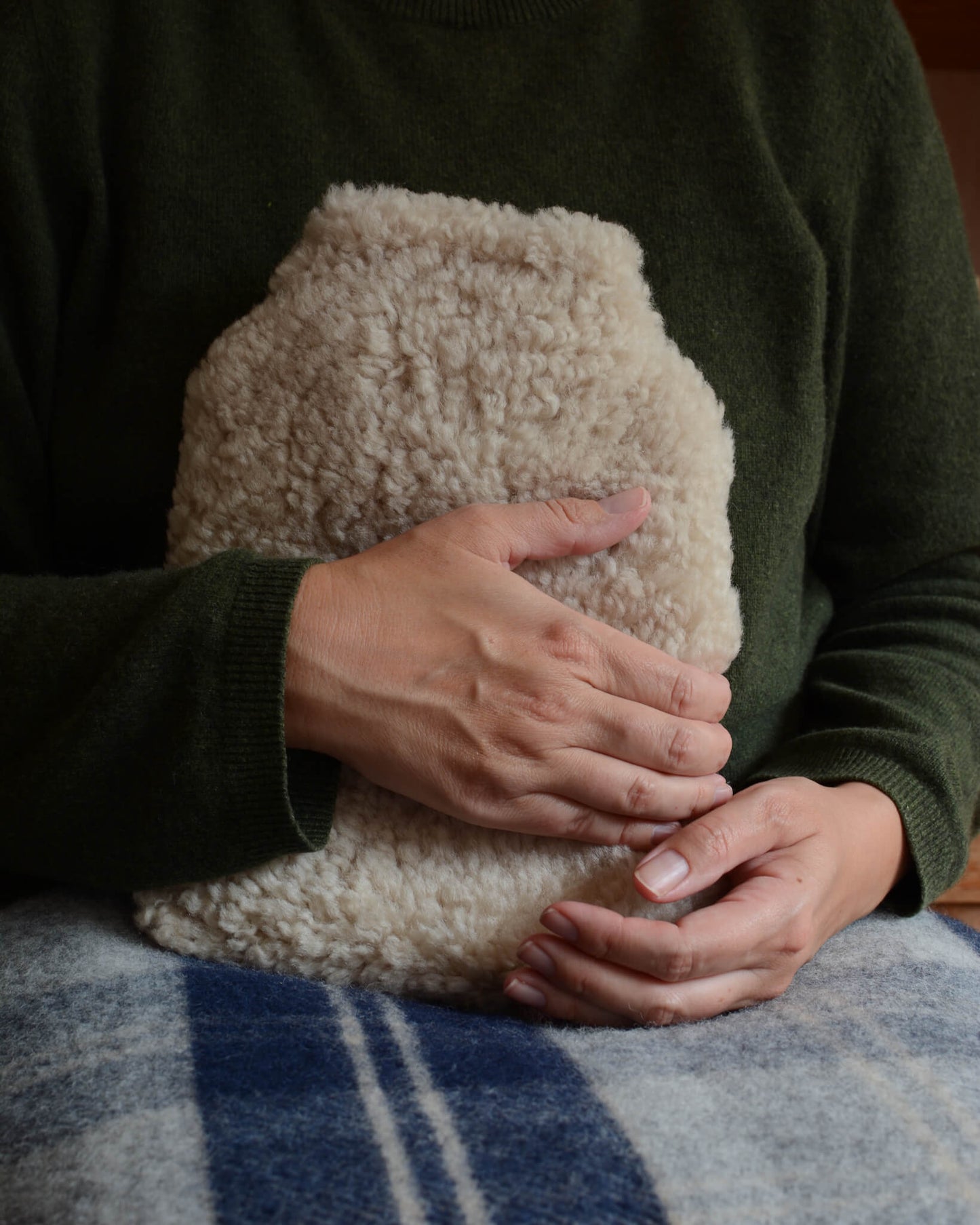 A person holding a natural sheepskin hot water bottle.