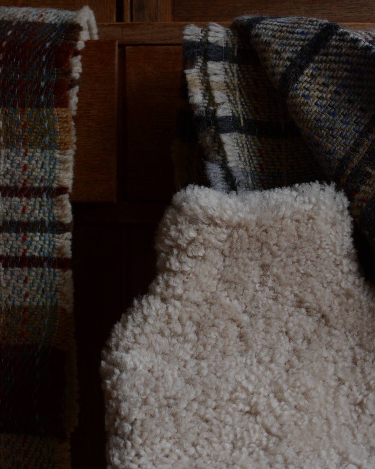 A close-up of a natural sheepskin hot water bottle, next to some woollen blankets.