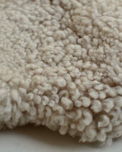 A close up of a natural sheepskin hot water bottle.