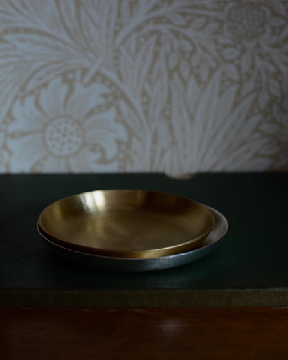 A solid brass candle dish, and a silver candle dish.