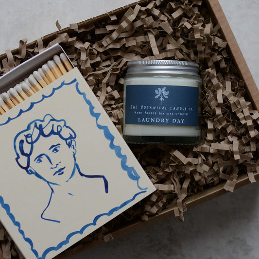 A candle gift box, containing a blue candle and a box of letterpress matches.