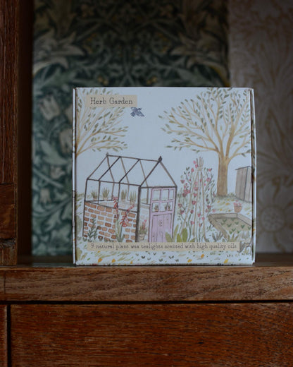 A box of tealights, with an illustrated box featuring a glasshouse within a summer garden.