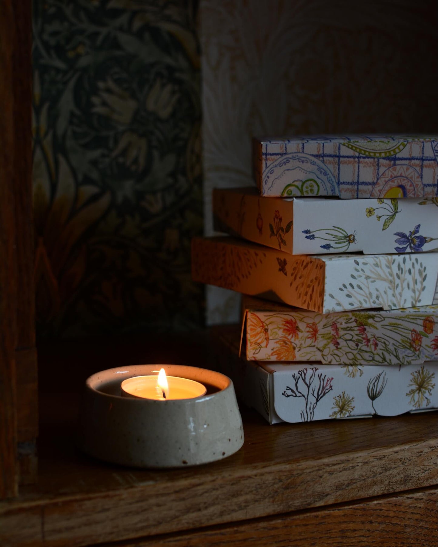 A lit scented tealight, inside of a ceramic gtealight holder. 