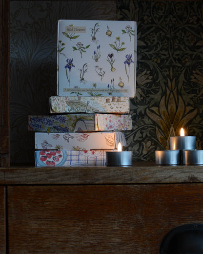 A selection of boxes of tealights, with botanical illustrations on the boxes.