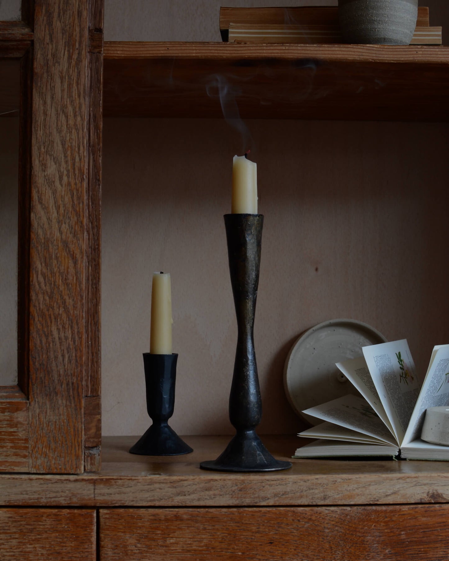 A pair of tall metal black candlesticks, forged from iron.