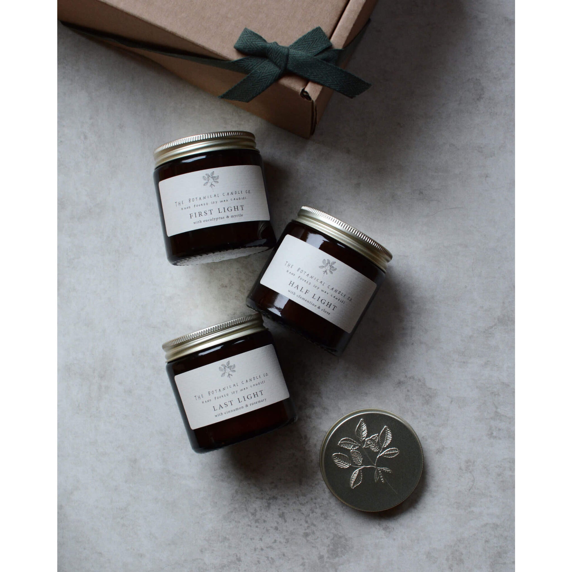 Amber glass jar candles next to a gift box with a green bow.