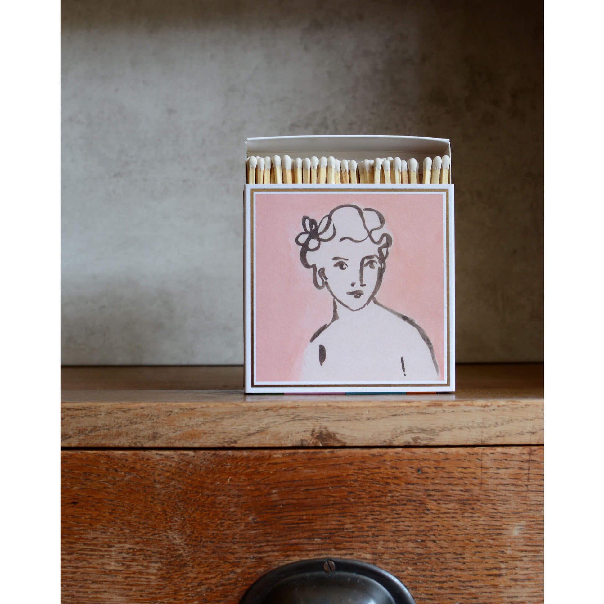 Pink matchbox with a portrait of a woman.