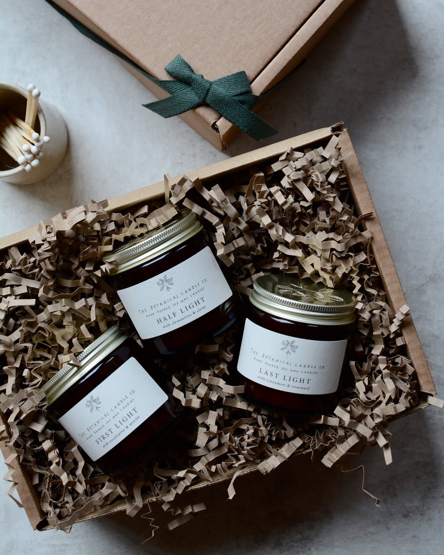 A trio of winter blend candles in amber glass jars, presented in a gift box.