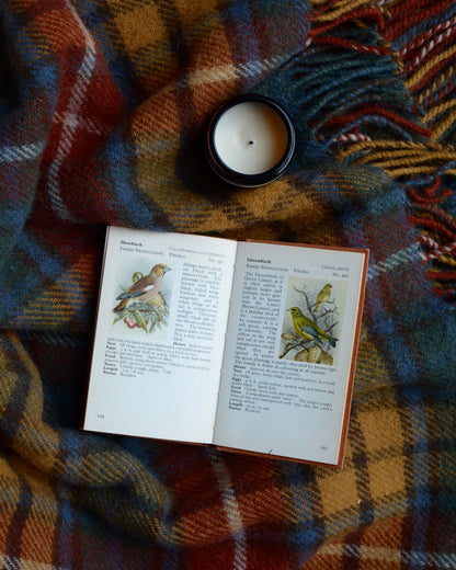 Multicoloured check wool blanket with a candle and book.