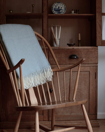 A duck egg herringbone weave blanket, on a wooden rocking chair.