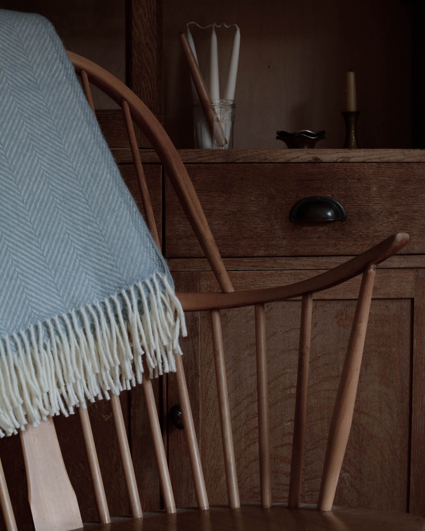 Detail shot of a duck egg herringbone weave blanket, on a wooden rocking chair.