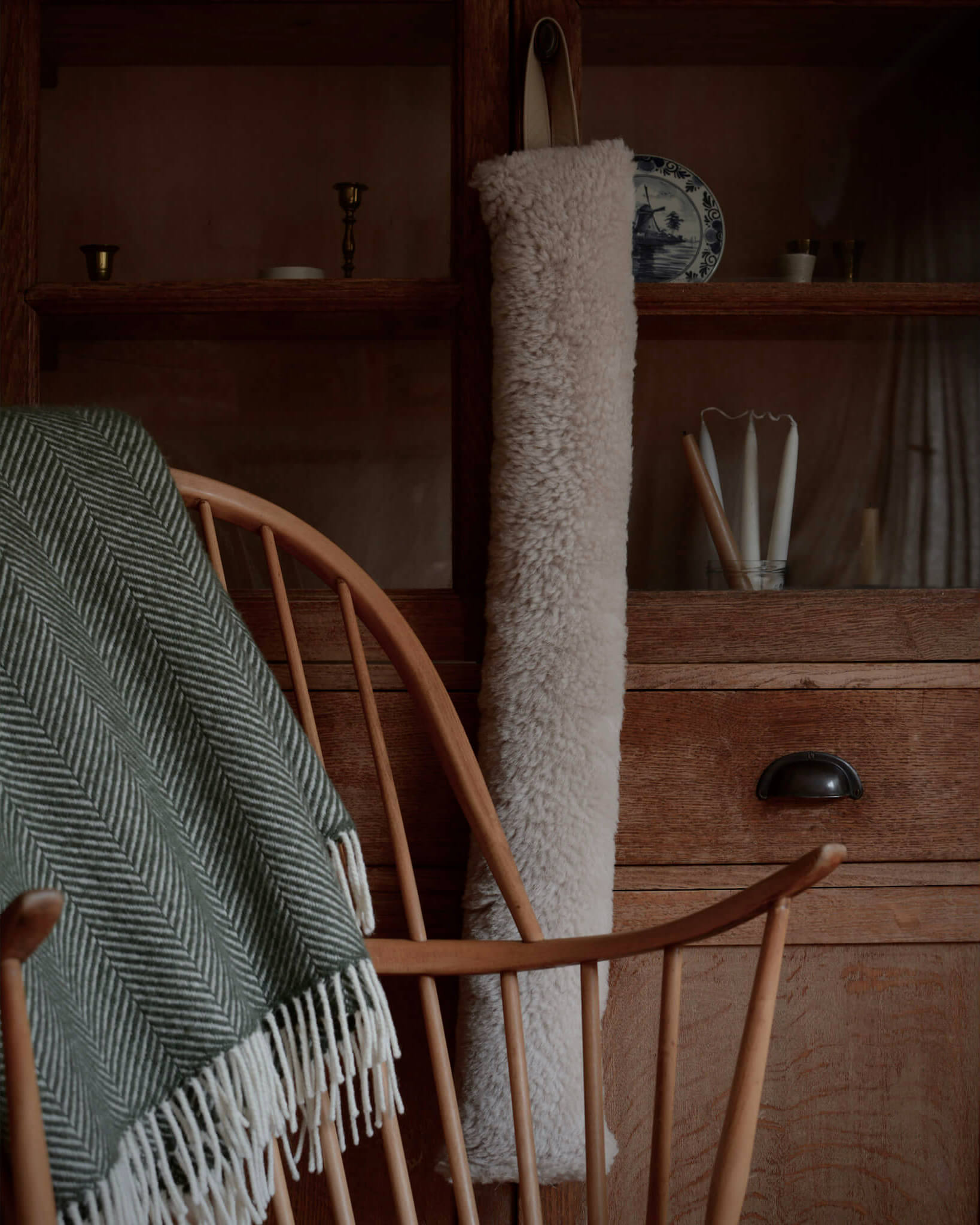 A green woollen herringbone blanket, resting on a wooden rocking chair.