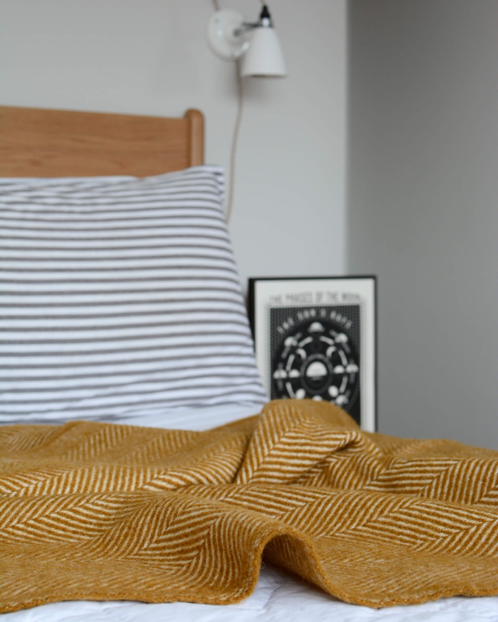 A mustard yellow wool herringbone blanket on top of a bed.