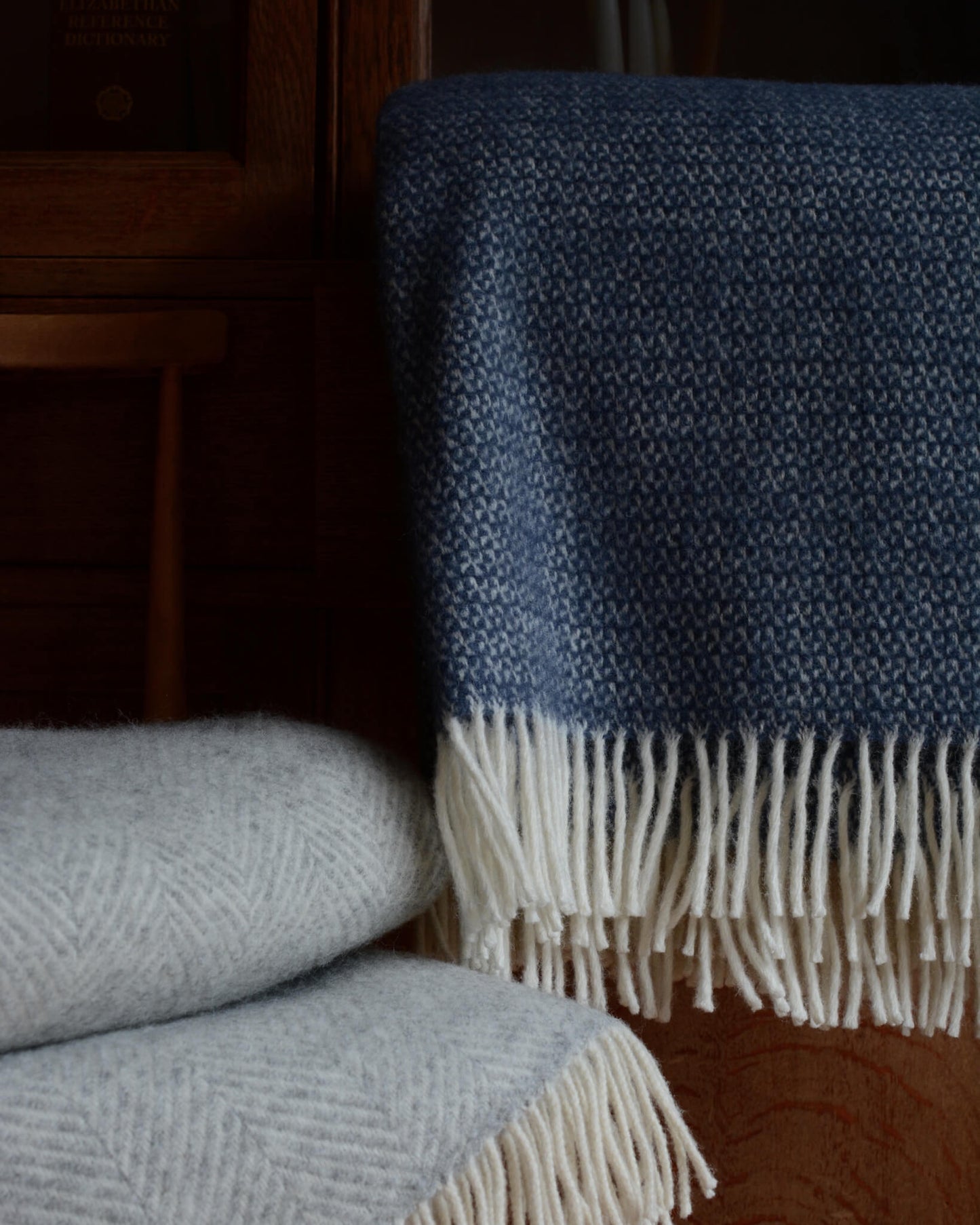 A blue wool windmill blanket, next to a grey wool blanket.