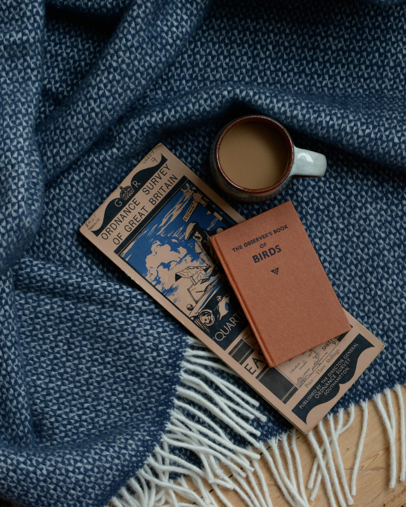 A blue woollen blanket, with a map and coffee cup.