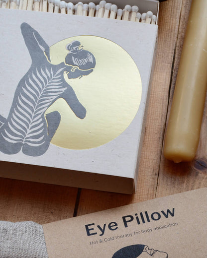 A close-up of a white match box featuring a yoga figure in front of a shiny gold moon. 